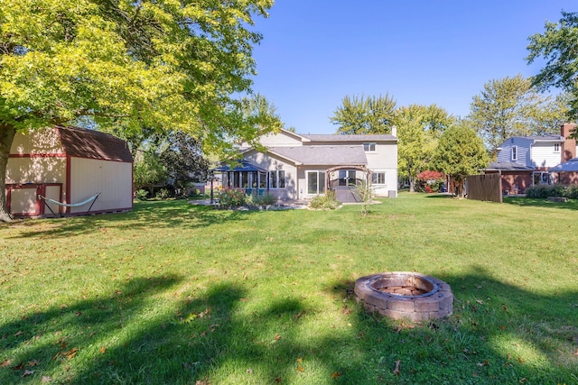 view of yard featuring a fire pit, a sunroom, and a storage shed