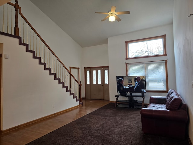 foyer entrance with ceiling fan, wood-type flooring, and a towering ceiling