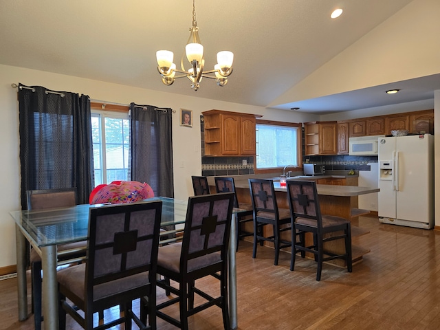 dining space featuring hardwood / wood-style flooring, high vaulted ceiling, a wealth of natural light, and a chandelier