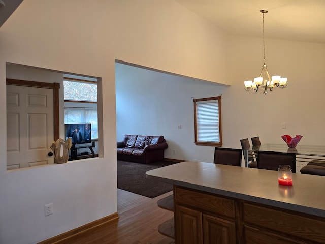 kitchen featuring hanging light fixtures, dark wood-type flooring, high vaulted ceiling, a notable chandelier, and a breakfast bar