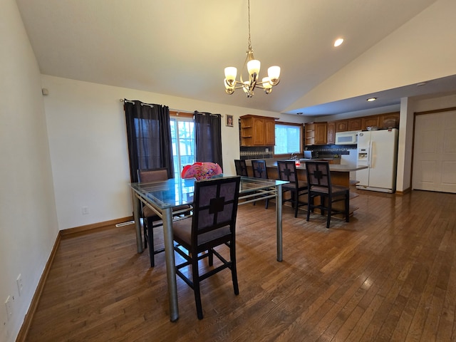 dining space featuring sink, dark wood-type flooring, a healthy amount of sunlight, and an inviting chandelier