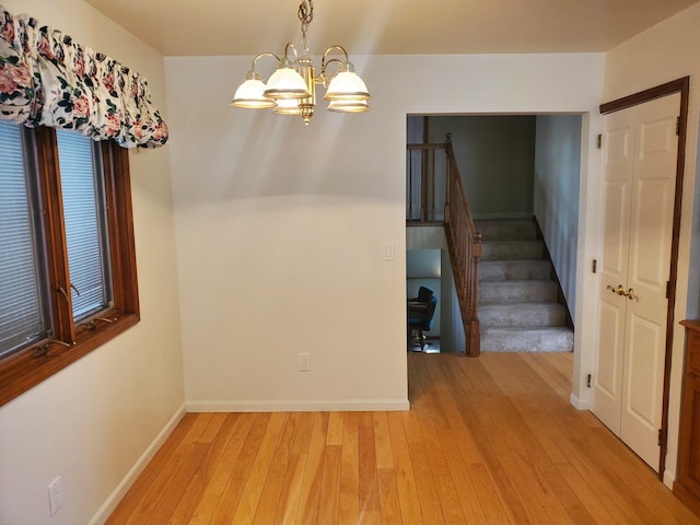 unfurnished dining area featuring light wood-type flooring and a notable chandelier