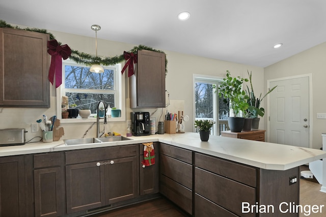 kitchen with lofted ceiling, sink, hanging light fixtures, dark hardwood / wood-style floors, and kitchen peninsula