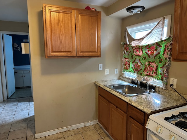 kitchen with light tile patterned flooring, white gas stove, and sink