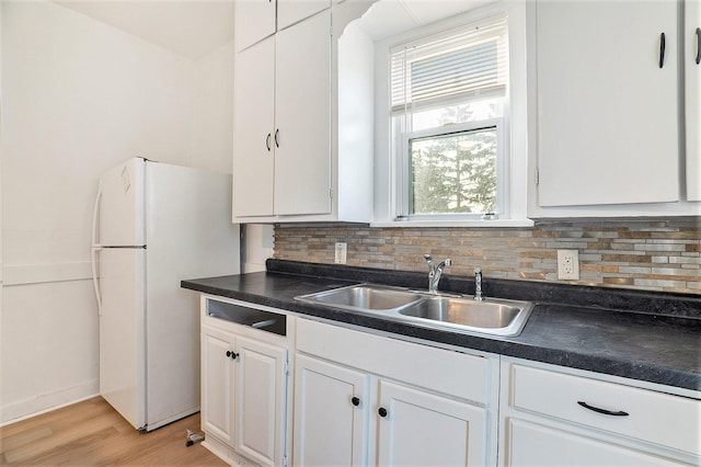 kitchen with white cabinets, sink, light hardwood / wood-style floors, tasteful backsplash, and white fridge