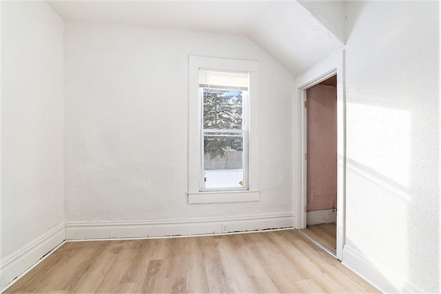 additional living space with light hardwood / wood-style floors and vaulted ceiling