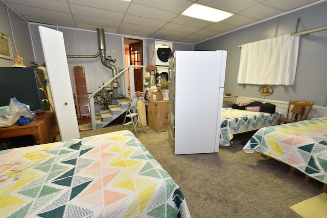 carpeted bedroom with white refrigerator and stacked washer / drying machine