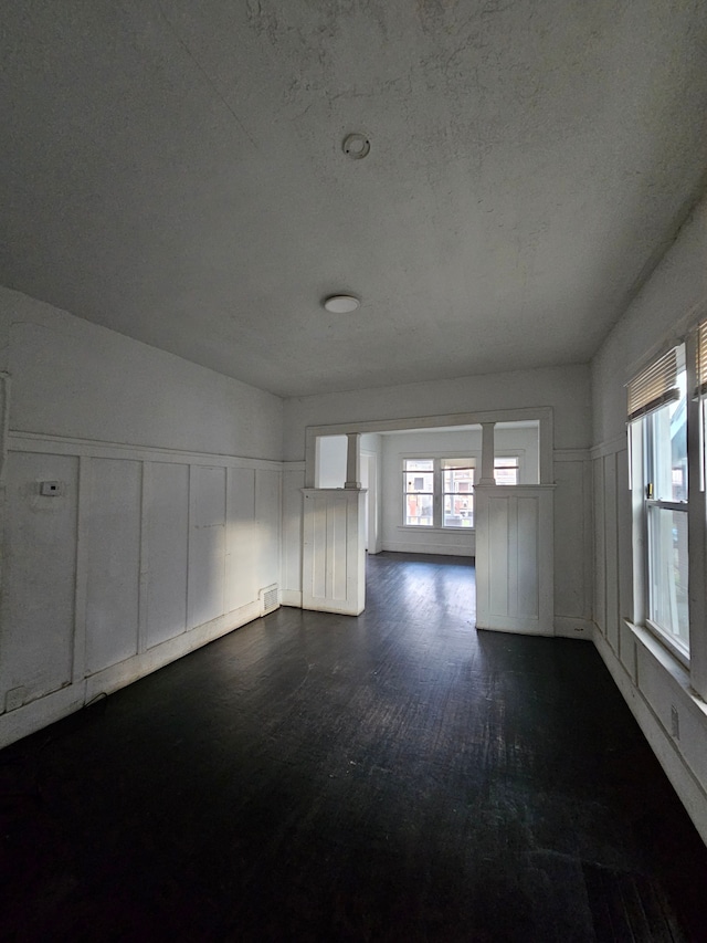 empty room with a textured ceiling, dark hardwood / wood-style floors, and lofted ceiling