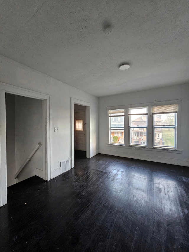 spare room featuring a textured ceiling and dark wood-type flooring