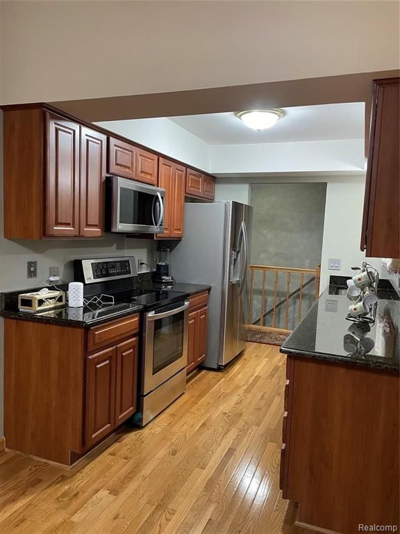 kitchen featuring dark stone counters, light wood-type flooring, and appliances with stainless steel finishes