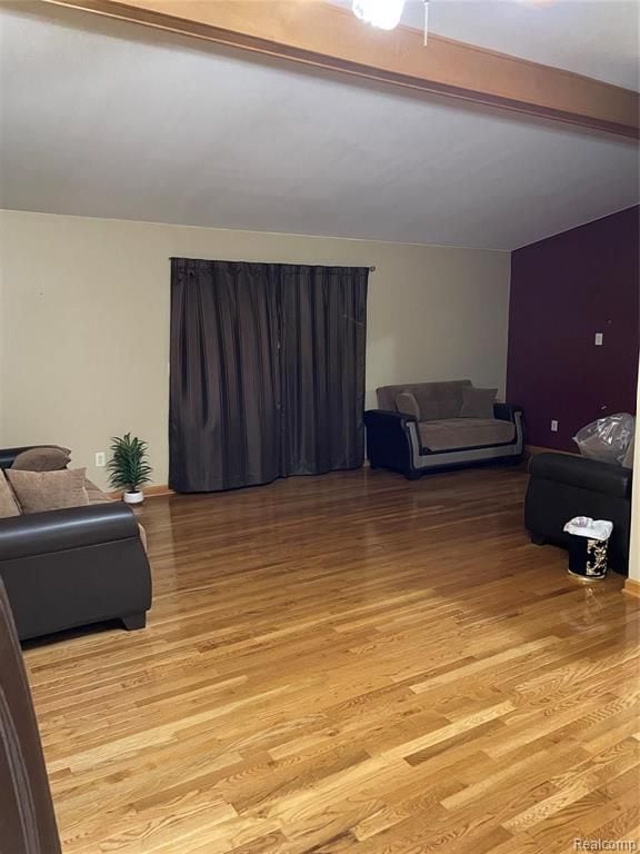 living room featuring beam ceiling and light wood-type flooring