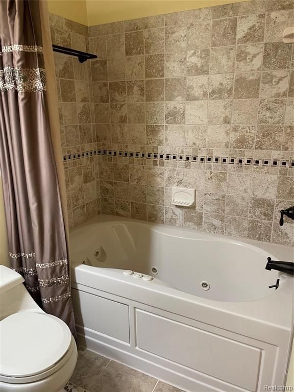 bathroom with tile patterned flooring, shower / bath combo, and toilet