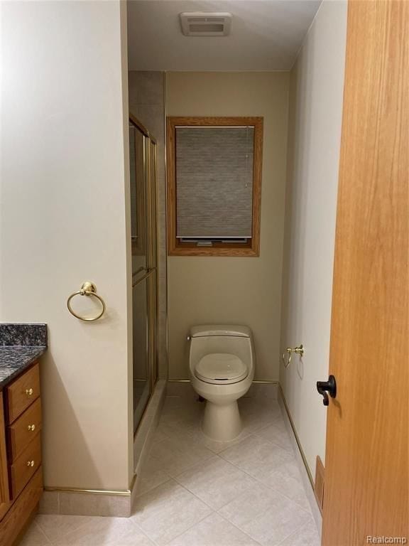 bathroom with tile patterned floors, vanity, toilet, and walk in shower