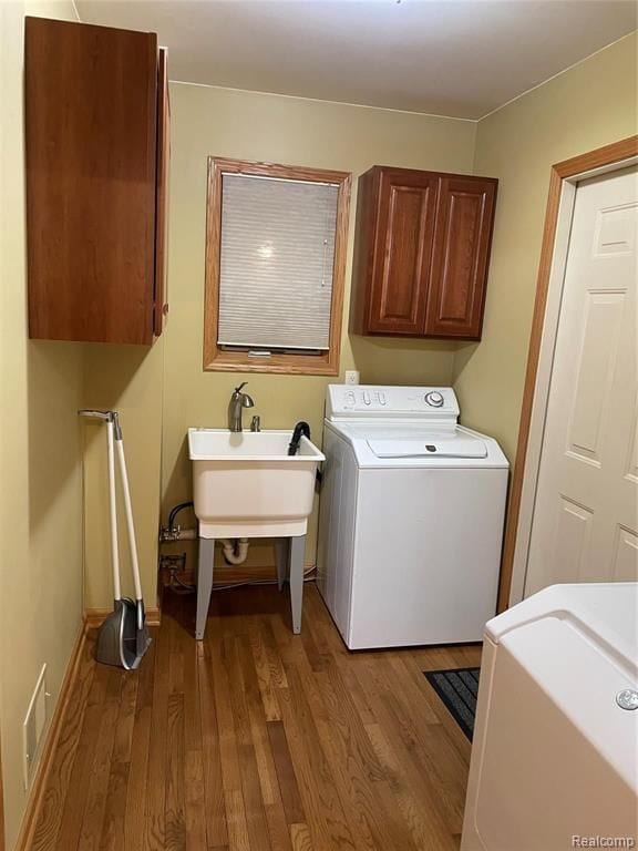 laundry area featuring sink, cabinets, light wood-type flooring, and washer / dryer