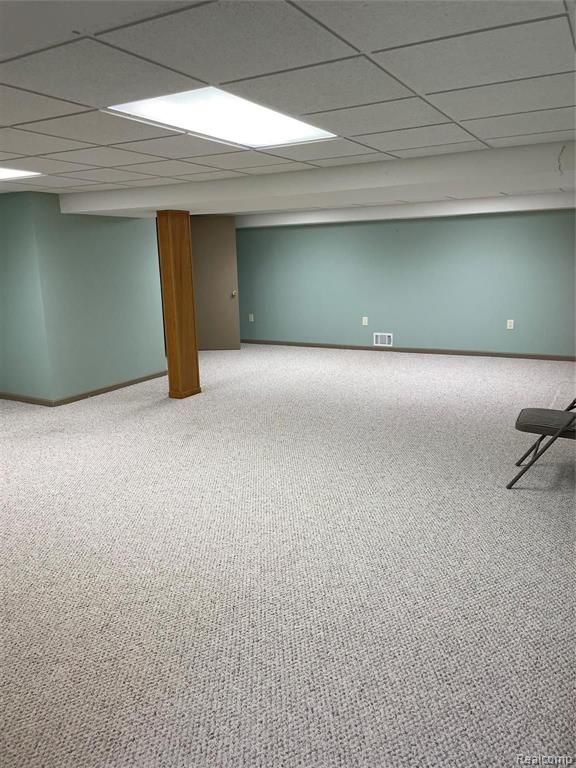 basement featuring a paneled ceiling and carpet flooring