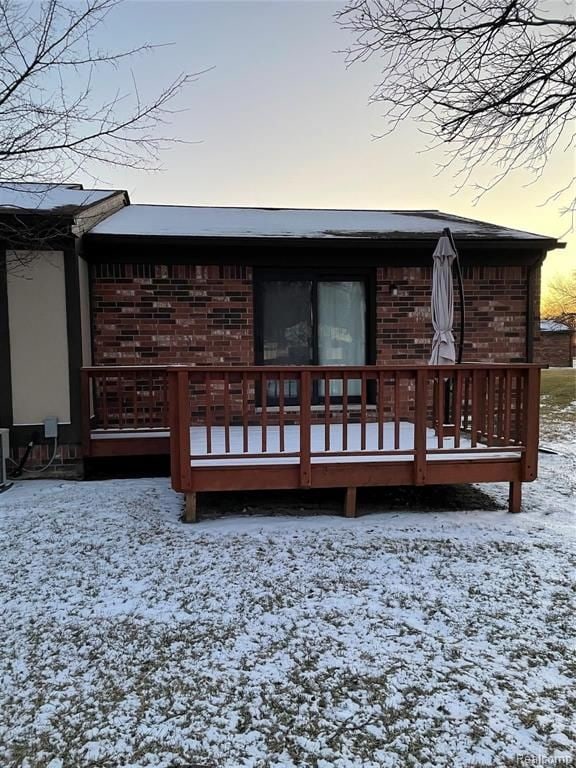 snow covered house featuring a deck and central AC unit