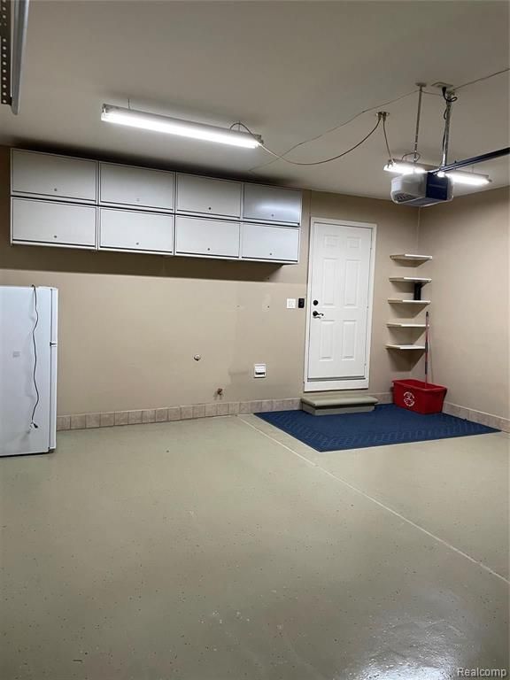 garage with white fridge and a garage door opener