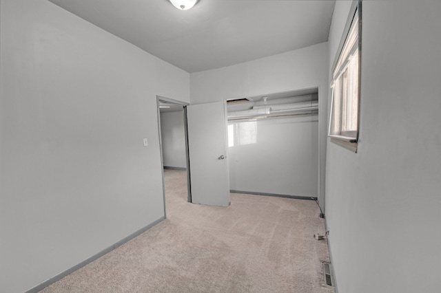 unfurnished bedroom featuring light colored carpet and a closet