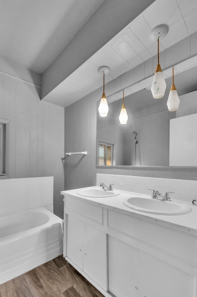 bathroom with hardwood / wood-style flooring, vanity, a tub to relax in, and wooden walls