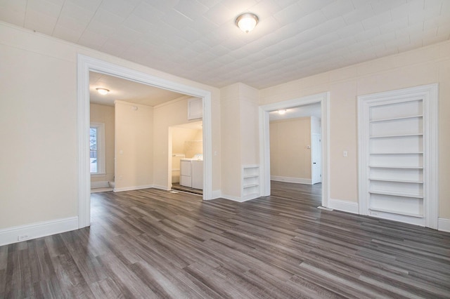 spare room with built in shelves, ornamental molding, dark wood-type flooring, and independent washer and dryer