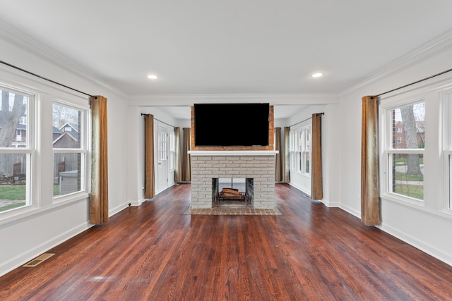 unfurnished living room featuring plenty of natural light, crown molding, and a brick fireplace