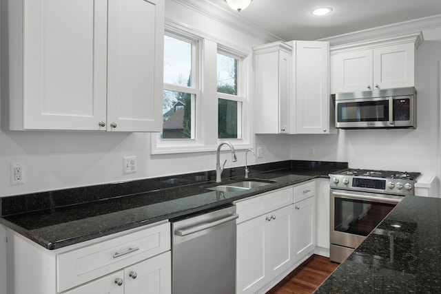 kitchen with crown molding, sink, dark stone countertops, white cabinetry, and stainless steel appliances