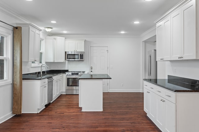 kitchen featuring white cabinets, appliances with stainless steel finishes, dark hardwood / wood-style flooring, and a center island