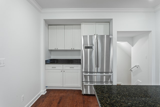 kitchen featuring stainless steel refrigerator, white cabinetry, dark hardwood / wood-style floors, dark stone countertops, and crown molding