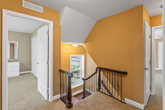 hallway with carpet floors and vaulted ceiling