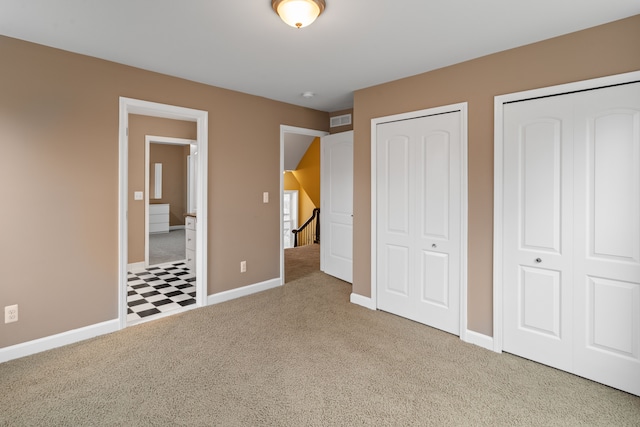 unfurnished bedroom with carpet floors and multiple closets