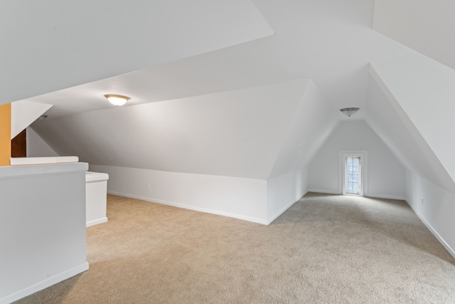 additional living space featuring light colored carpet and vaulted ceiling