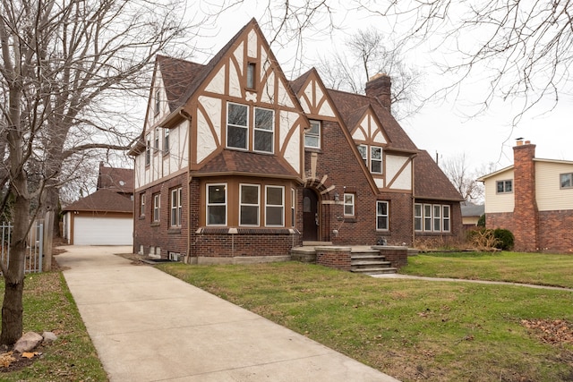 tudor house with a front lawn, an outdoor structure, and a garage