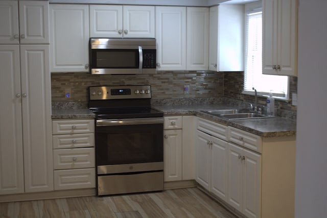 kitchen featuring appliances with stainless steel finishes, sink, a wealth of natural light, and white cabinets