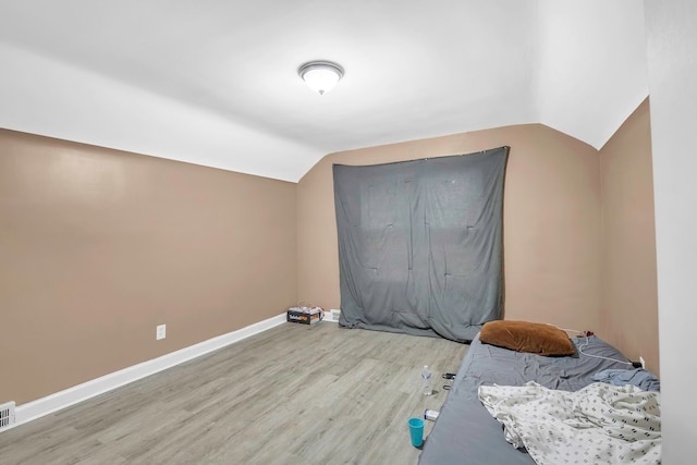 unfurnished bedroom with light hardwood / wood-style flooring and vaulted ceiling