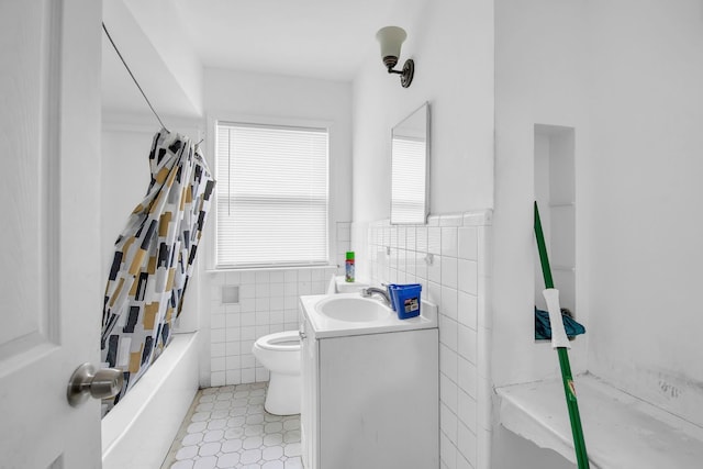 full bathroom with vanity, shower / tub combo with curtain, tile walls, tile patterned flooring, and toilet