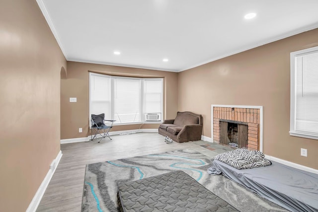 interior space featuring a brick fireplace, cooling unit, wood-type flooring, and ornamental molding