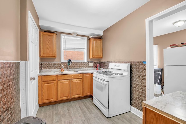 kitchen featuring tile walls, sink, white appliances, and light wood-type flooring