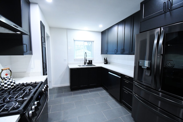 kitchen with black appliances, sink, wall chimney exhaust hood, dark tile patterned floors, and tasteful backsplash