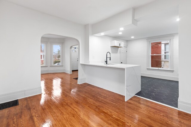 kitchen featuring white cabinets, sink, dark hardwood / wood-style floors, kitchen peninsula, and a breakfast bar