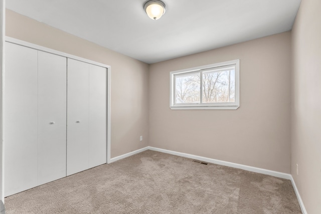 unfurnished bedroom with light colored carpet and a closet