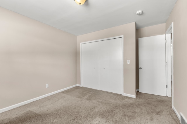 unfurnished bedroom featuring light carpet and a closet