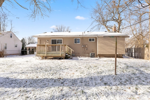 snow covered back of property with central AC unit and a wooden deck