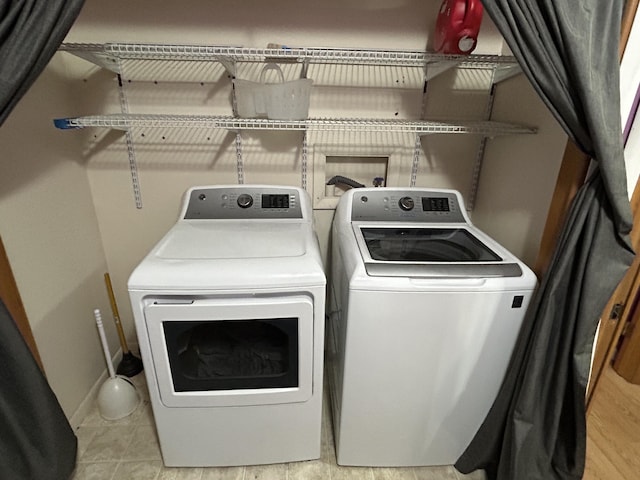 laundry area with washer and dryer and light tile patterned floors