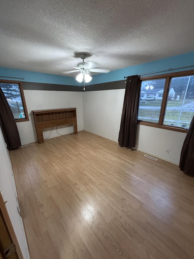 interior space featuring a textured ceiling, light hardwood / wood-style flooring, and ceiling fan