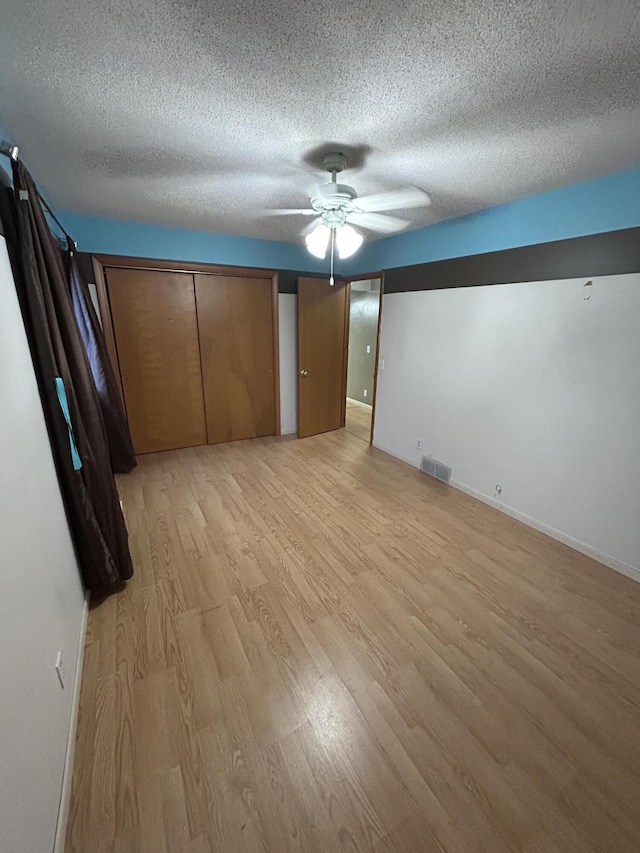 unfurnished bedroom with a textured ceiling, light hardwood / wood-style floors, and ceiling fan