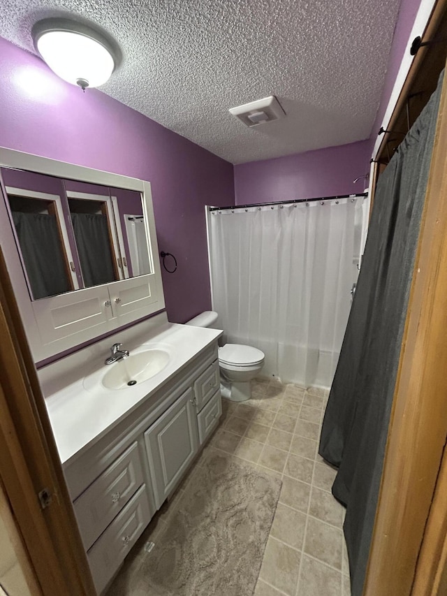 bathroom featuring a shower with curtain, vanity, a textured ceiling, tile patterned flooring, and toilet