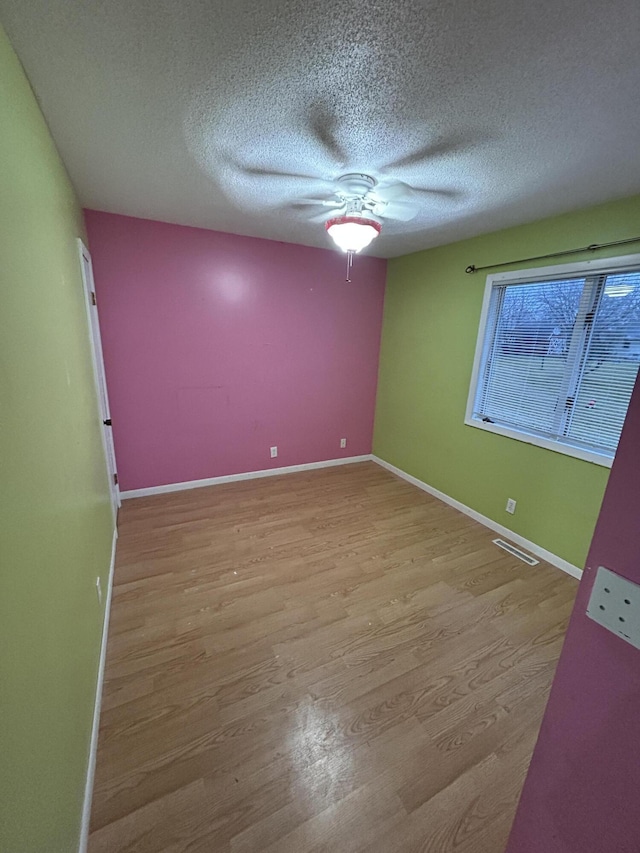 empty room with light wood-type flooring and a textured ceiling