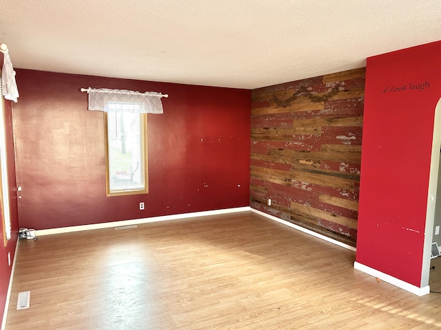 spare room with wood walls, hardwood / wood-style floors, and a textured ceiling