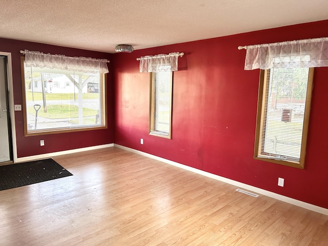 unfurnished dining area featuring a textured ceiling and hardwood / wood-style flooring