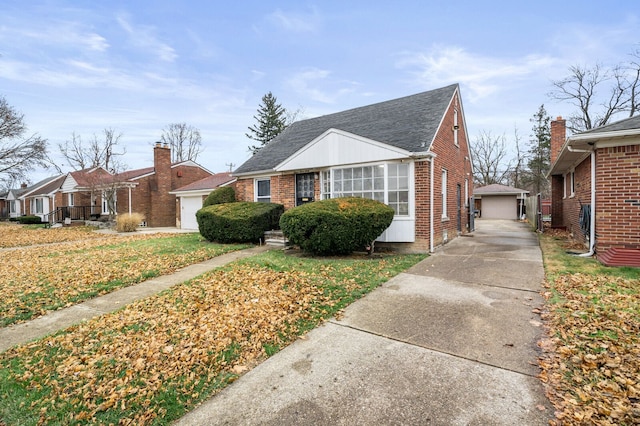 bungalow with a front yard, a garage, and an outdoor structure